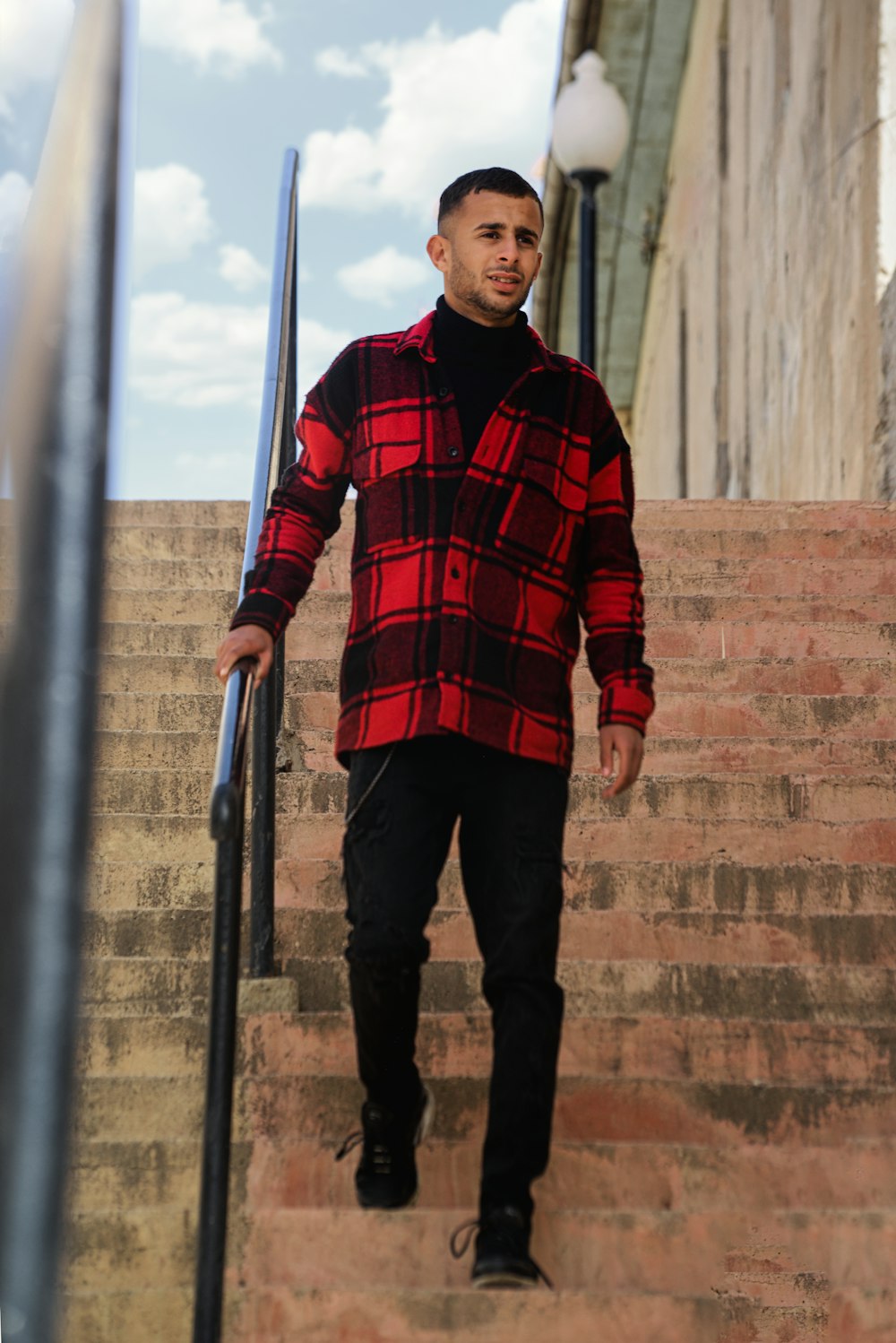 a man in a red and black jacket is walking up some stairs
