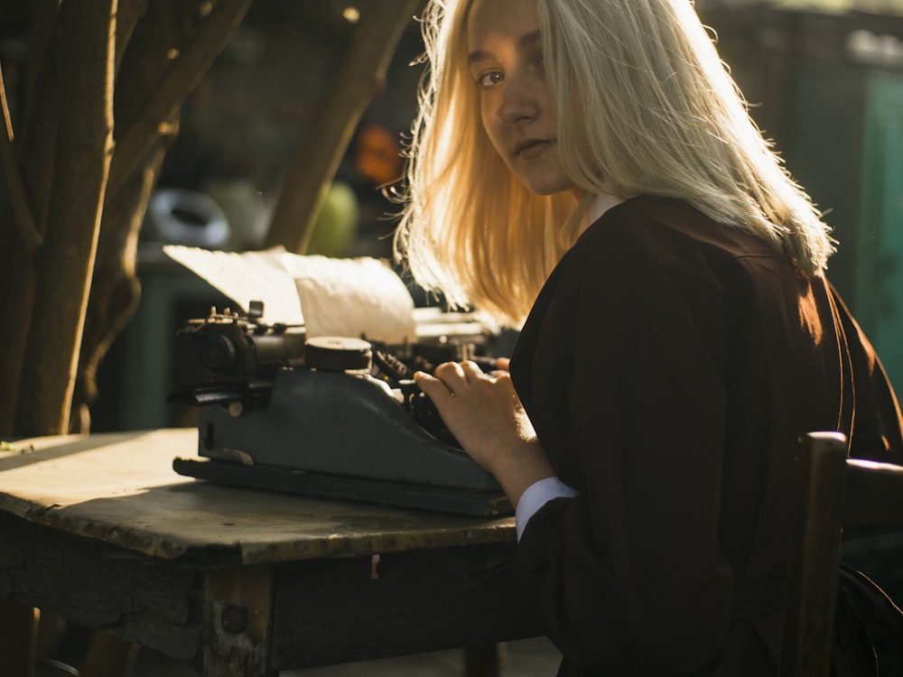 a woman sitting at a table typing on an old fashioned typewriter
