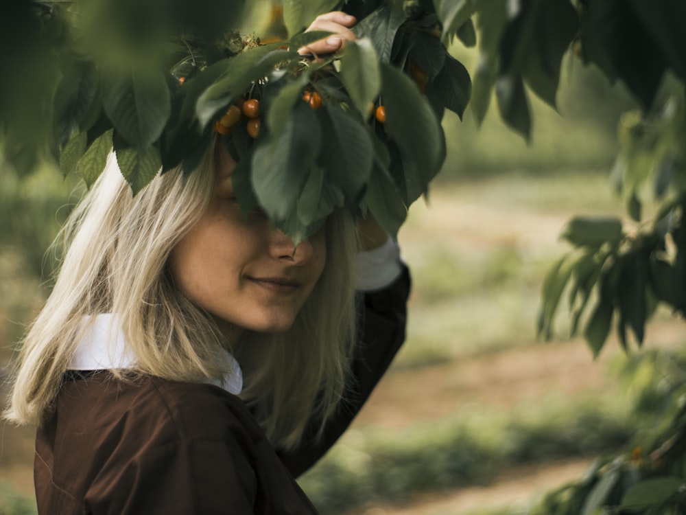 a woman is hiding behind a tree