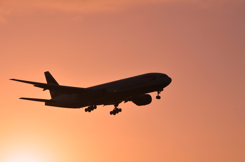 a large jetliner flying through a sunset sky