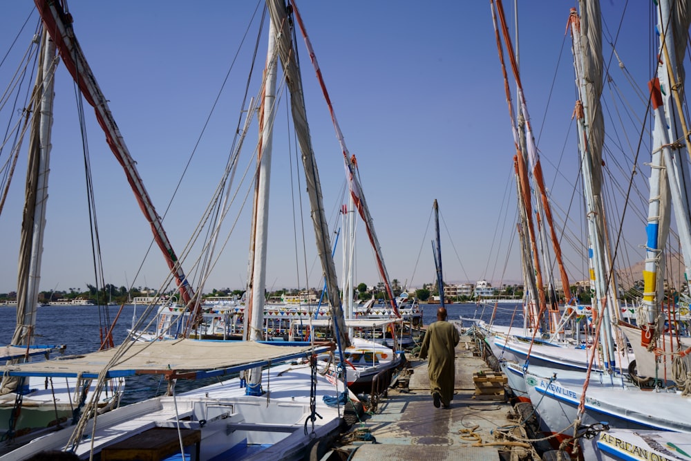 a man walking down a dock next to a bunch of boats
