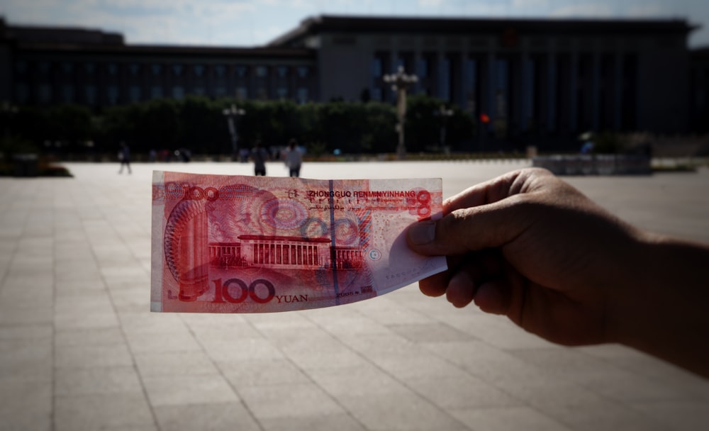 Una persona sosteniendo un pedazo de papel con una imagen de un edificio en el fondo