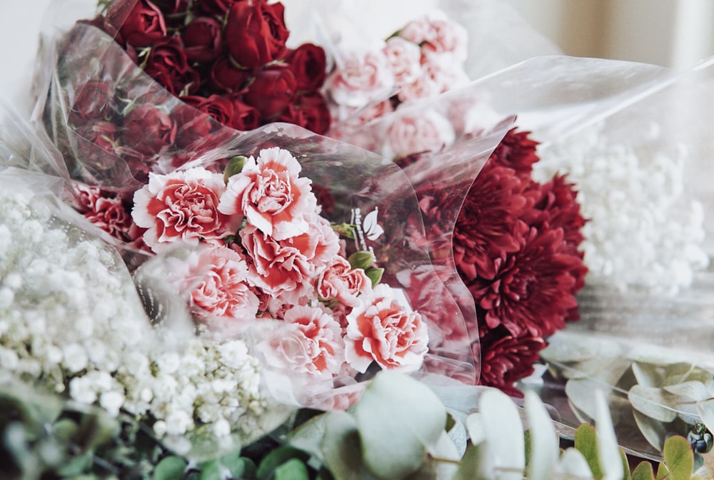 테이블 위에 앉아 있는 빨간색과 흰색 꽃 한 무리