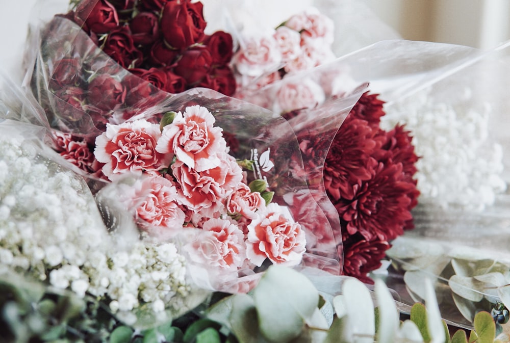 a bunch of red and white flowers sitting on top of a table