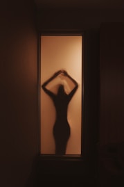 a woman standing in front of a window in a dark room