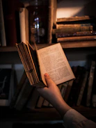 A robot hand holding a vintage book under soft lighting.