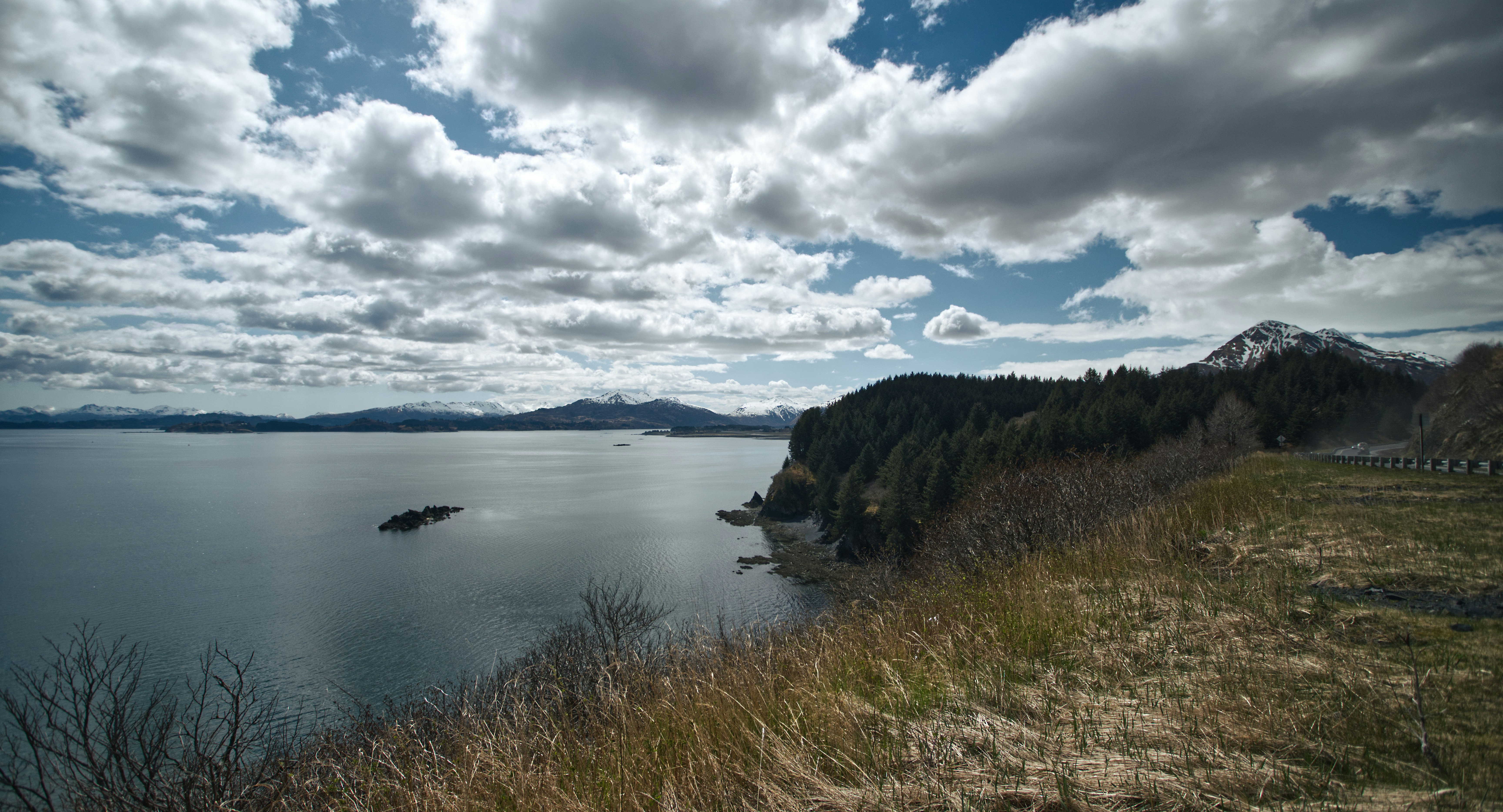 a large body of water sitting next to a lush green hillside