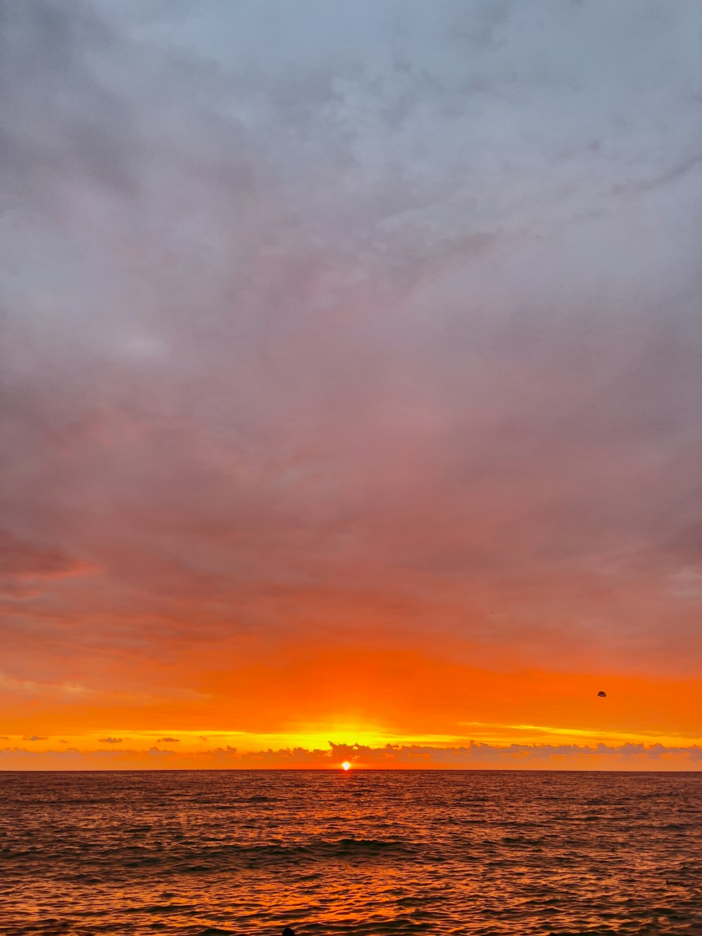 the sun is setting over the ocean on a cloudy day