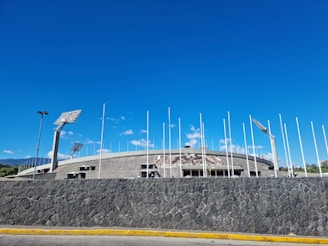 a stone wall with flags and a building in the background