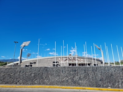 a stone wall with flags and a building in the background