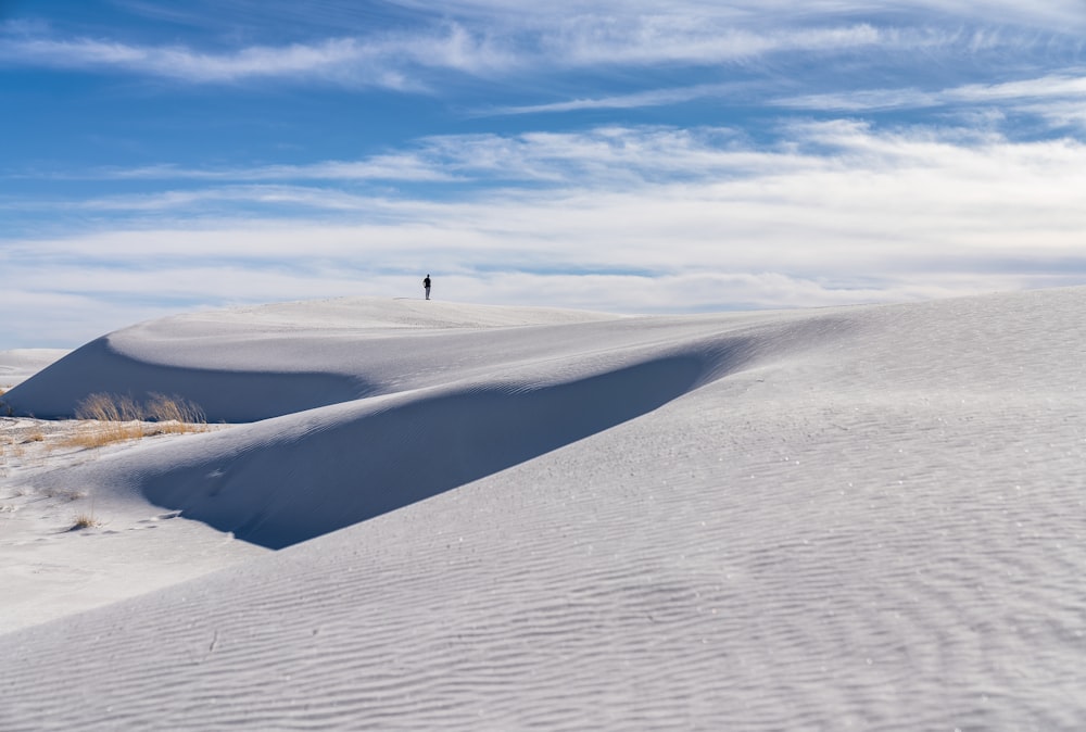 Una persona parada en la cima de una colina cubierta de nieve