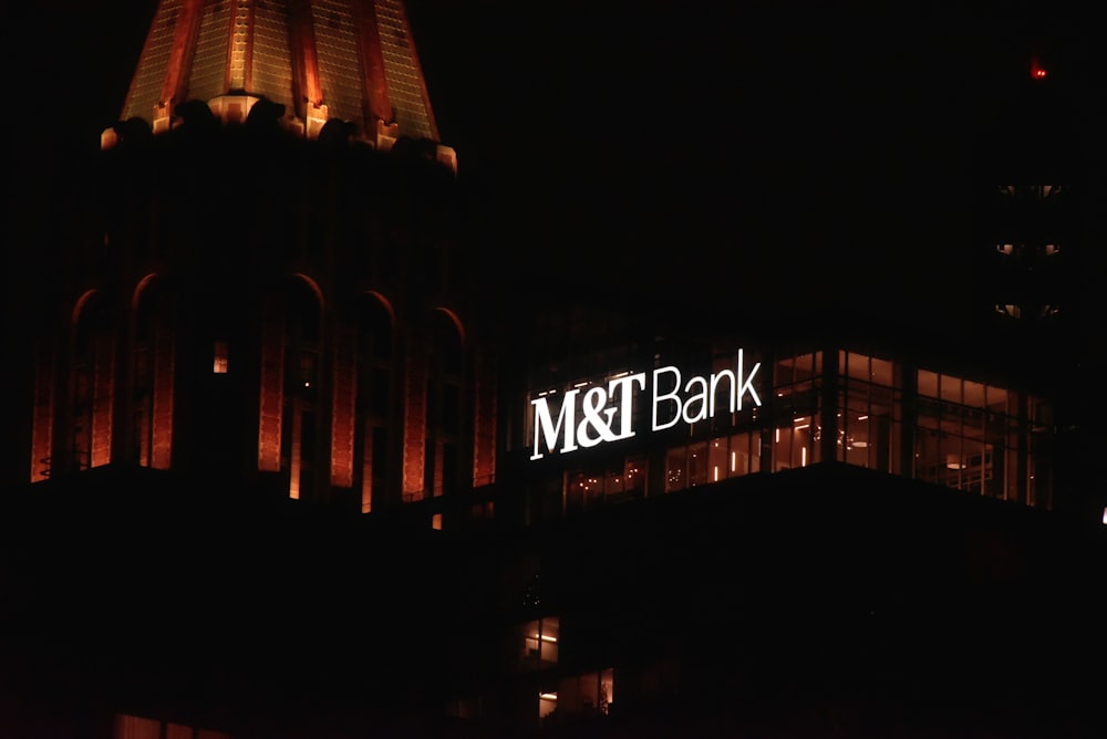 a building with a sign that says mt & t bank lit up at night