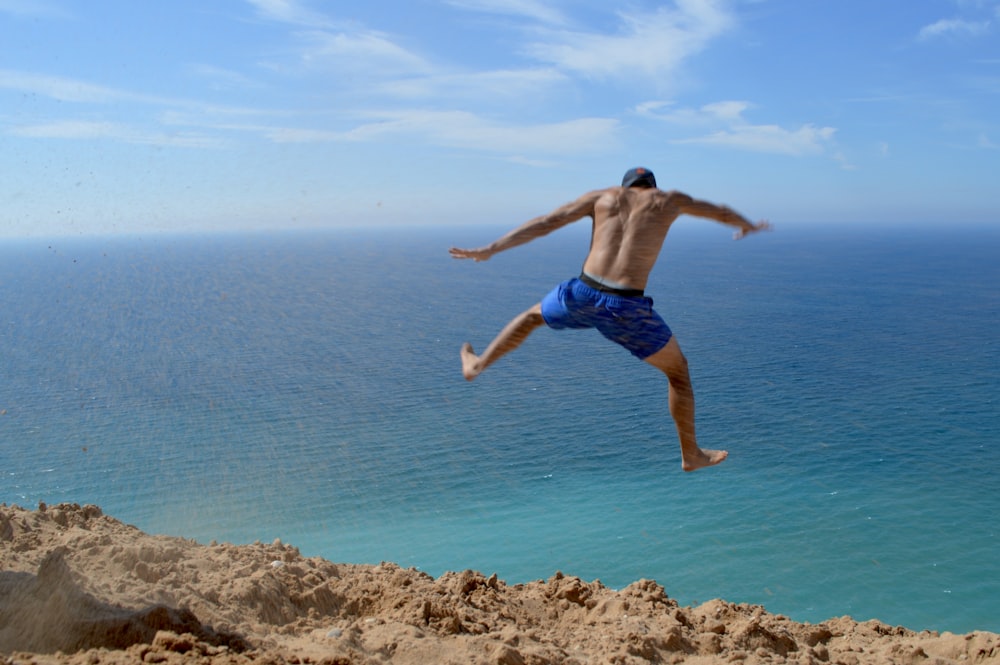 a man jumping off a cliff into the ocean