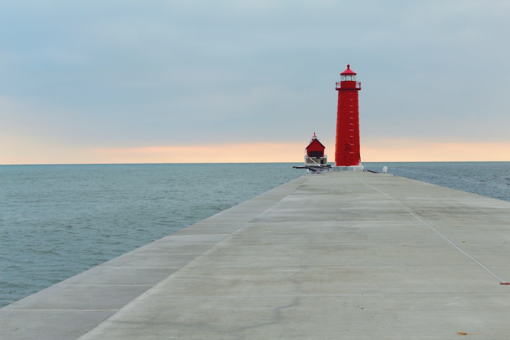 a red light house sitting on the end of a pier