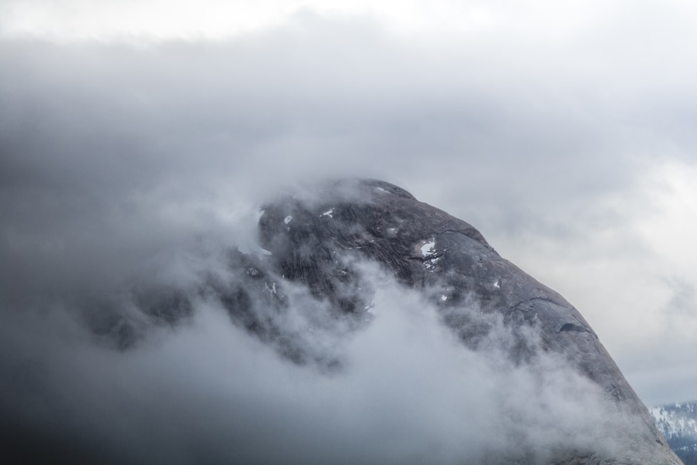 a mountain covered in fog and clouds on a cloudy day