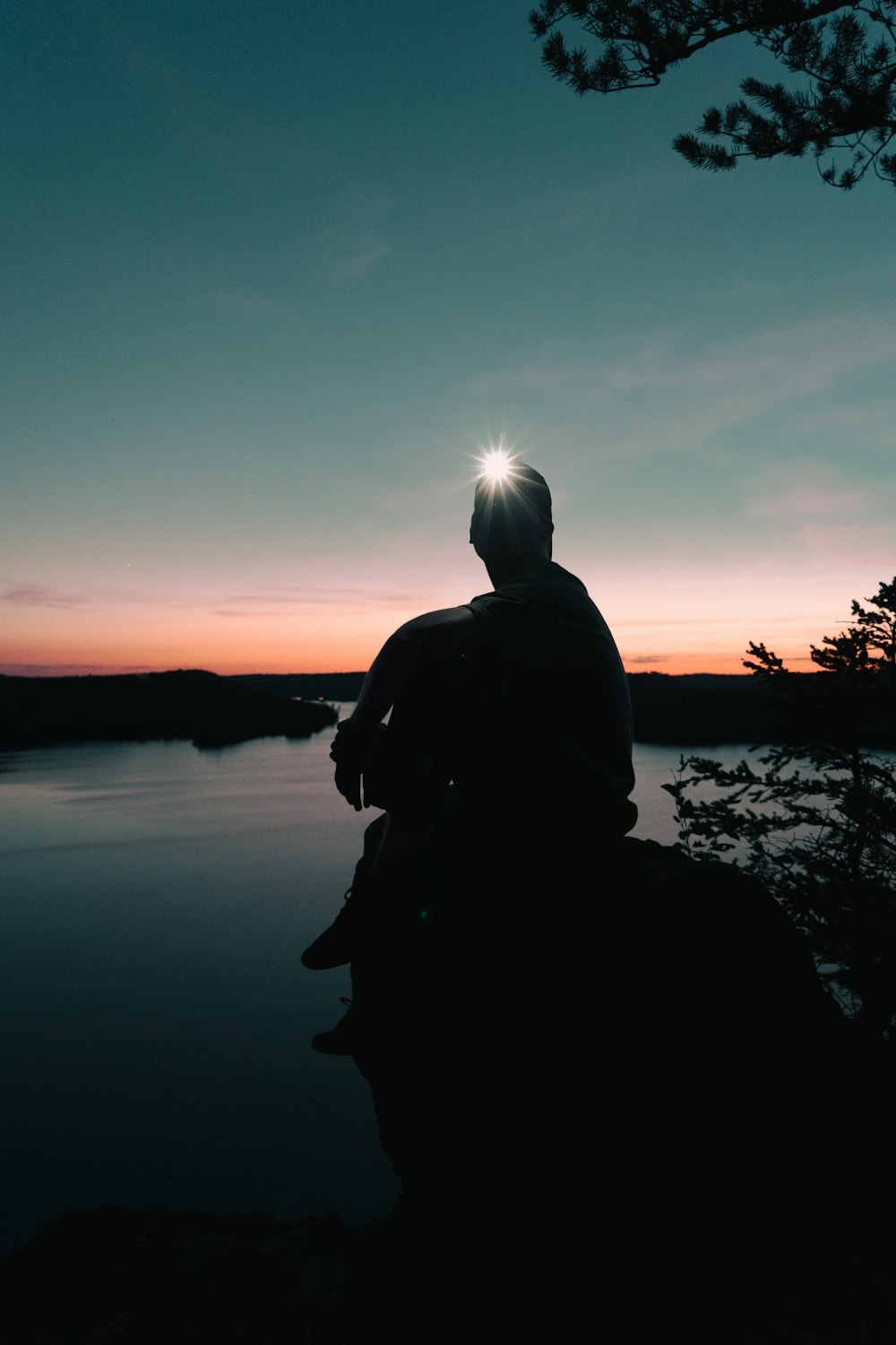 a man sitting on a rock looking out at the water