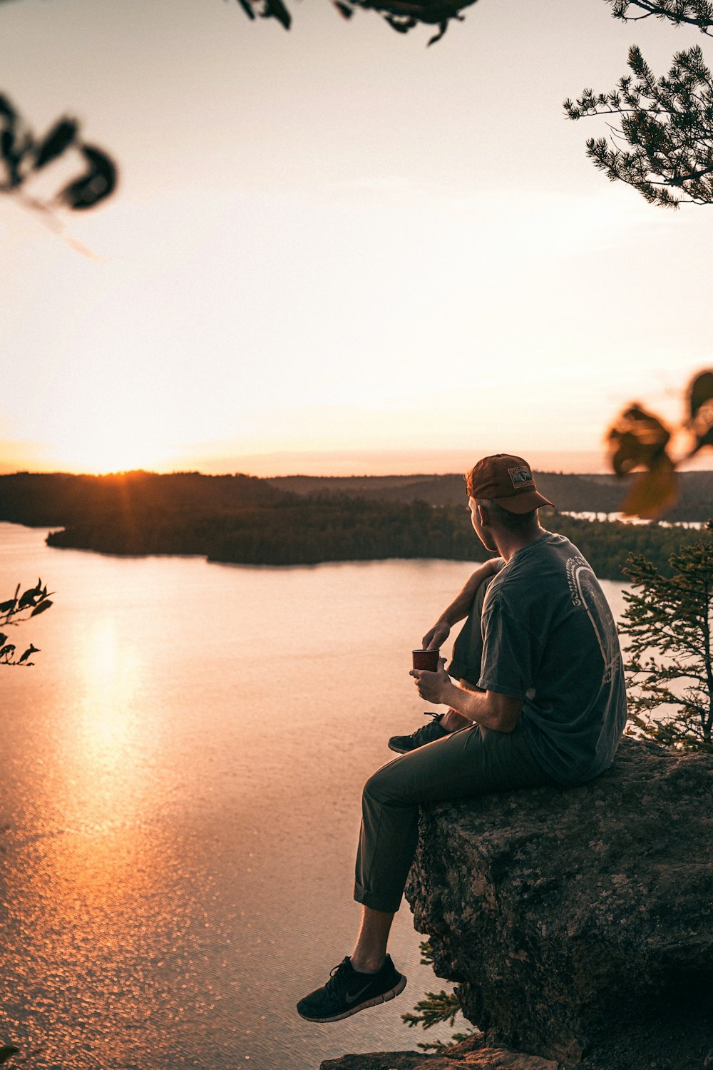 a man sitting on top of a rock next to a body of water