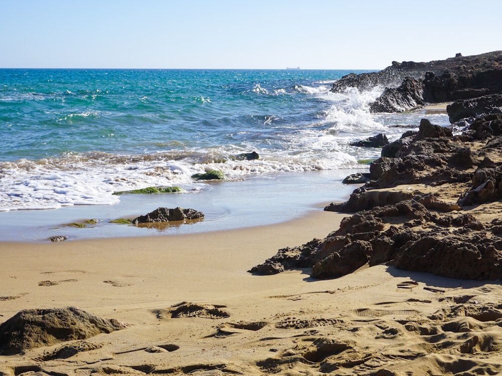 a sandy beach next to a body of water