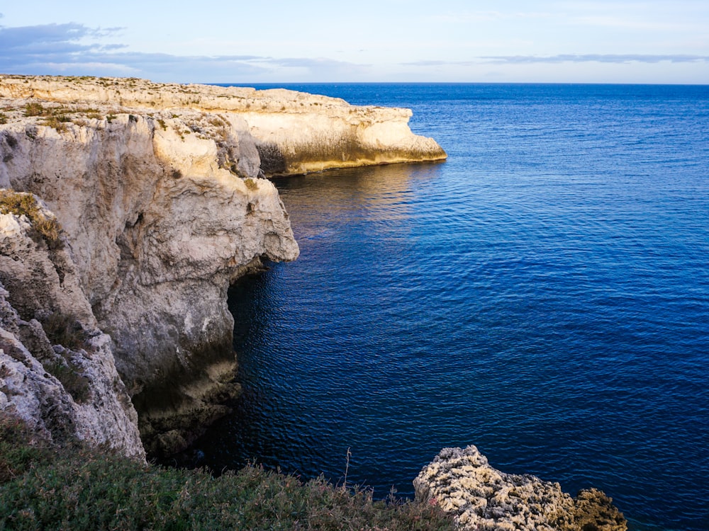 a large body of water next to a rocky cliff