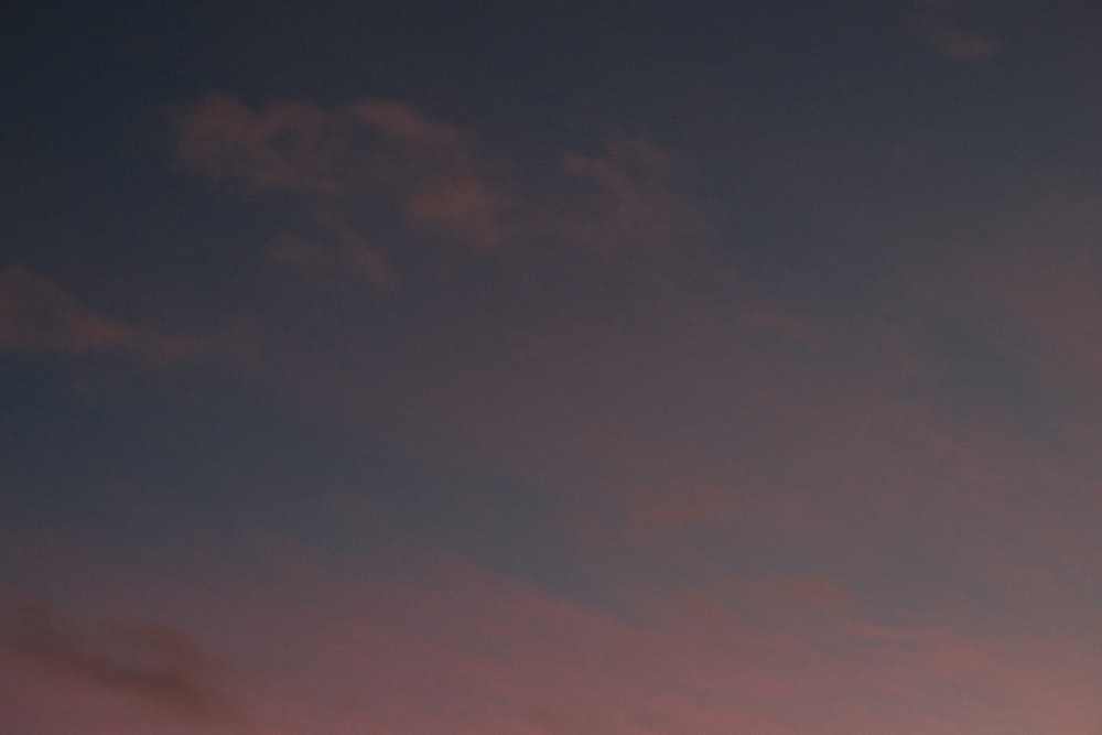 a plane flying in the sky at sunset