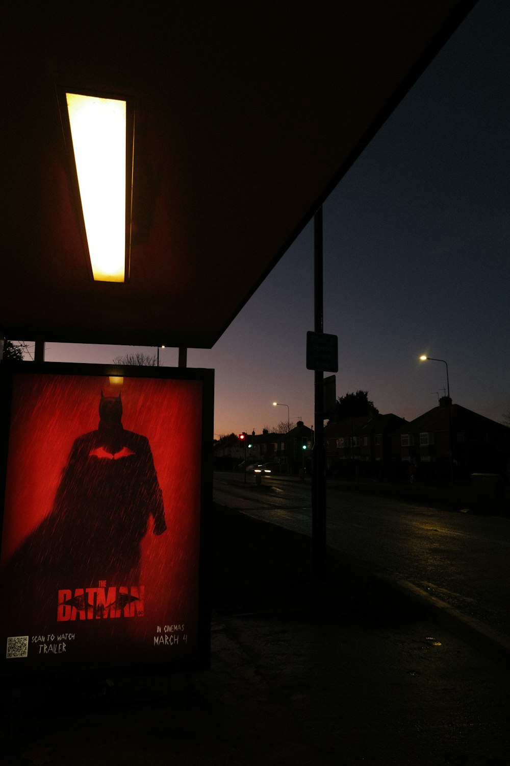 a batman movie poster on the side of the road