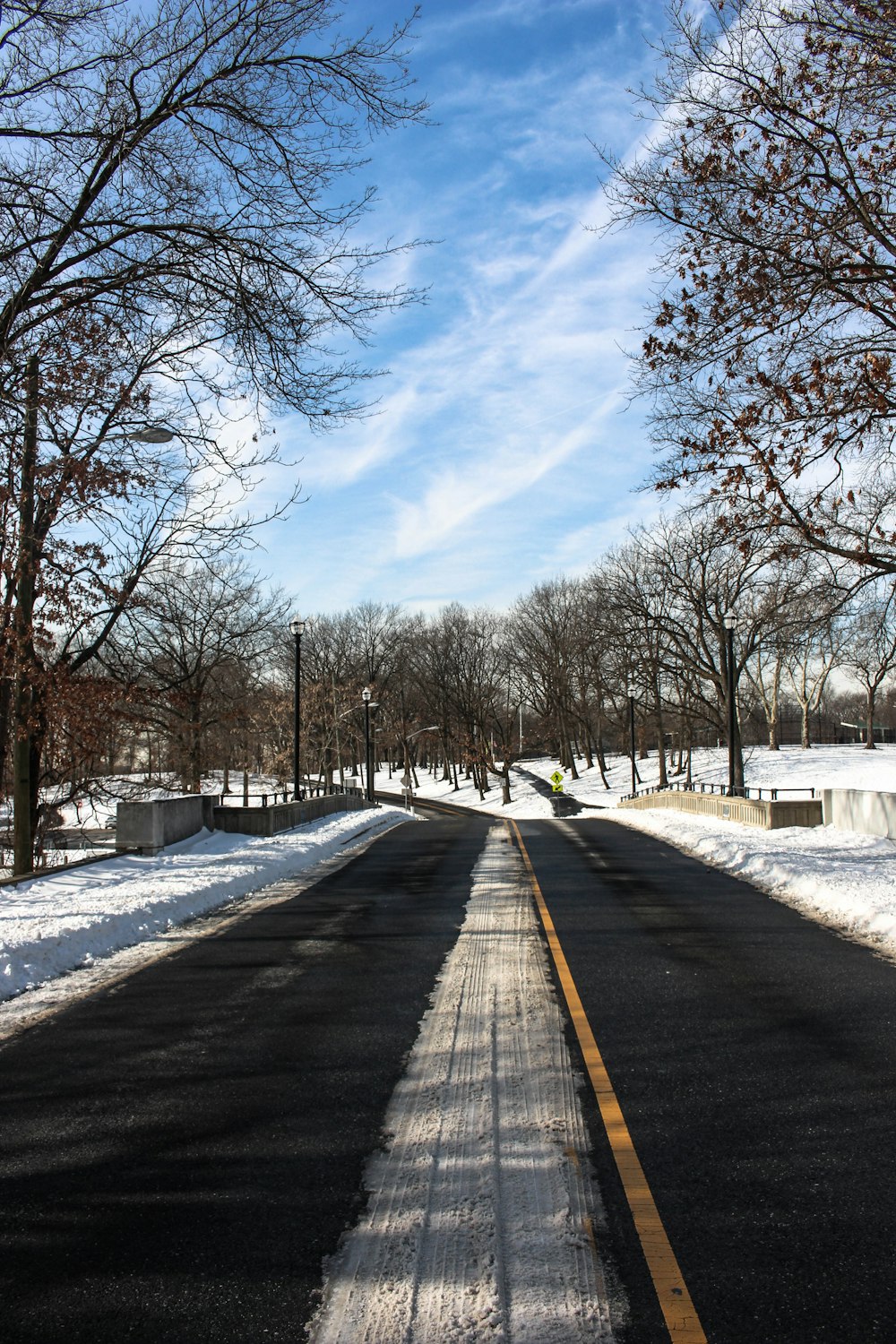 a street with snow on the ground and trees in the background