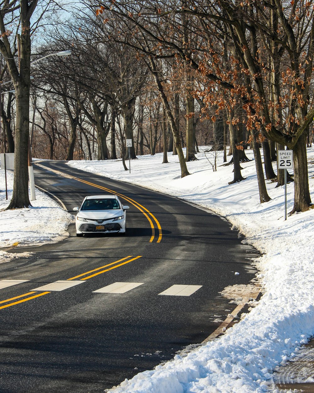 a white car driving down a snow covered road