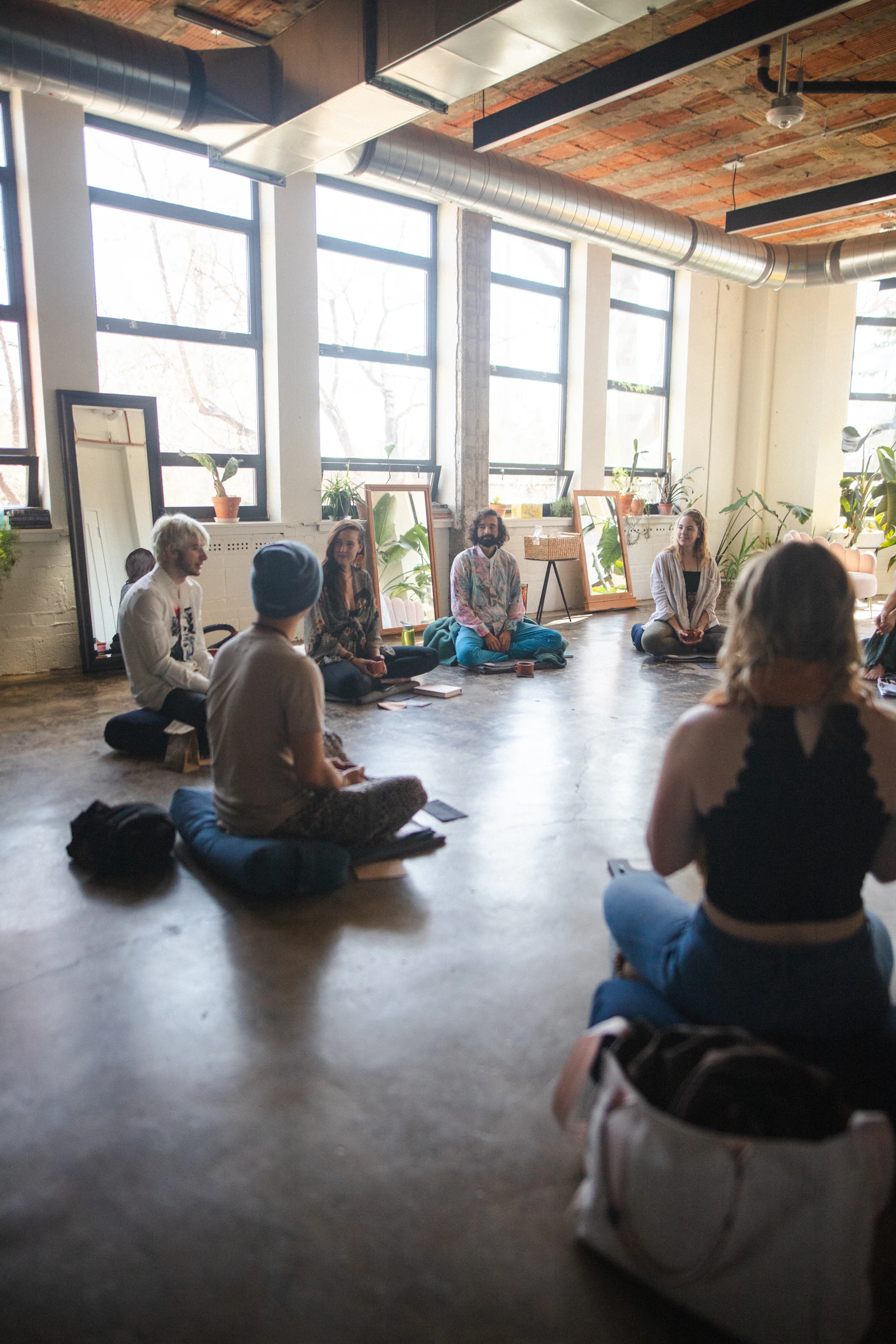 Students seated on the floor of the shala during a live-streamed session