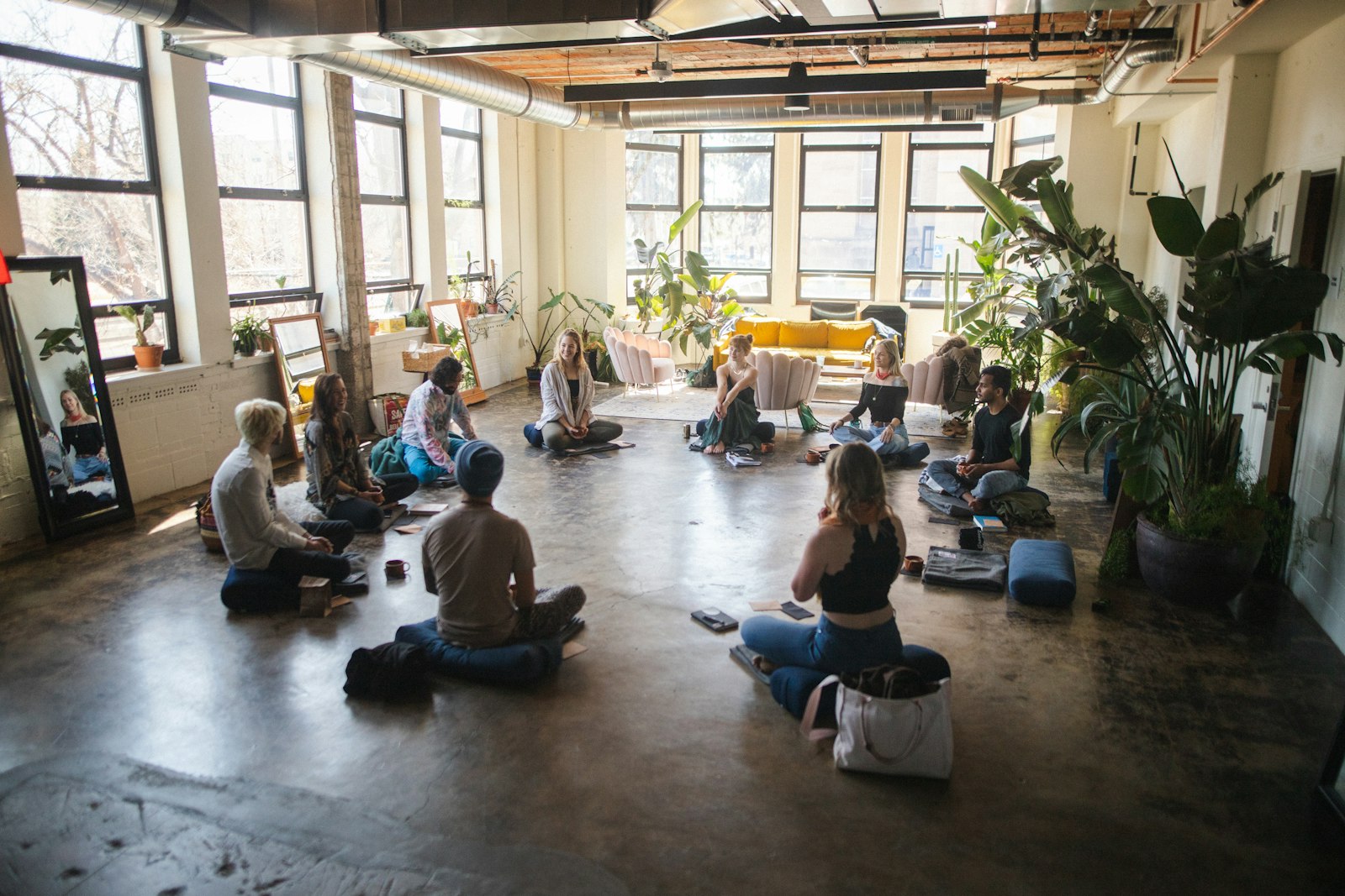 Group of people seated in a circle indoors, warm ambient light, contemplative cohort setting