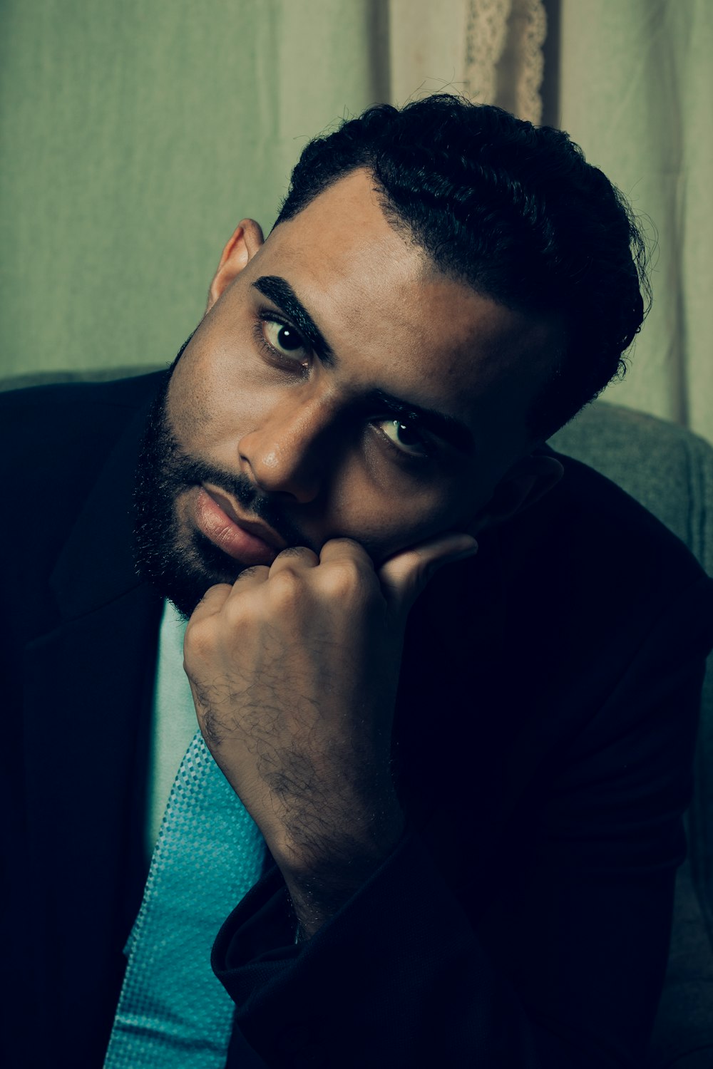 a man sitting in a chair with his hand on his chin