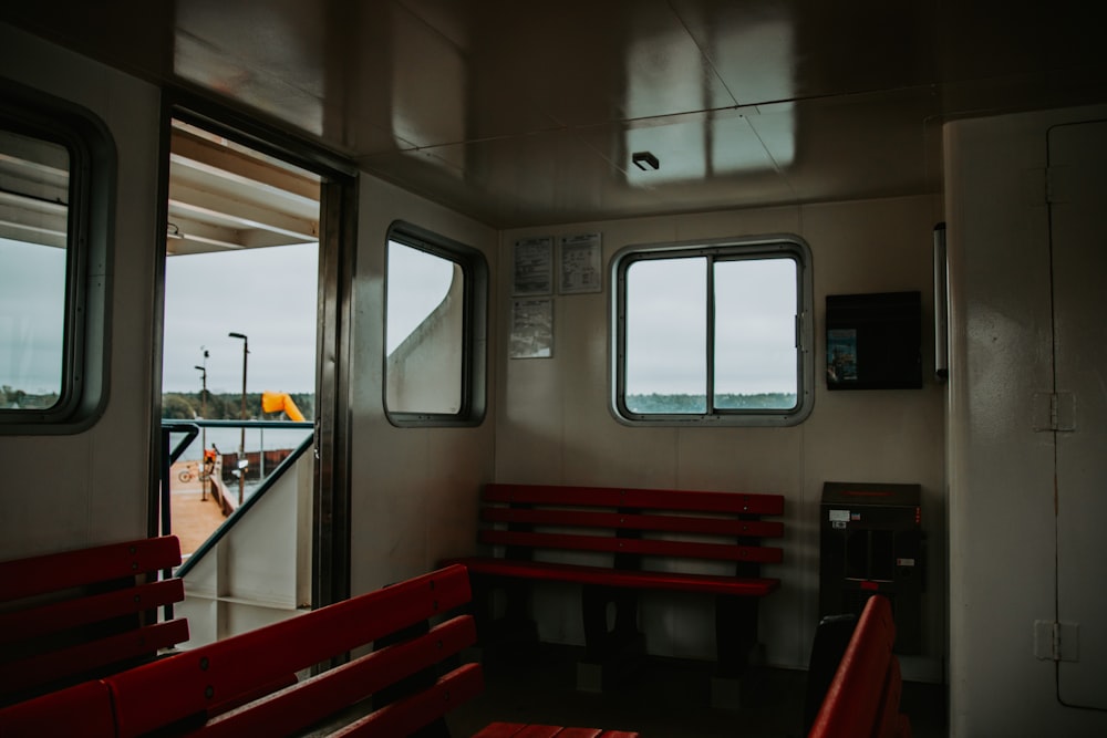 a red bench sitting next to a window on a boat