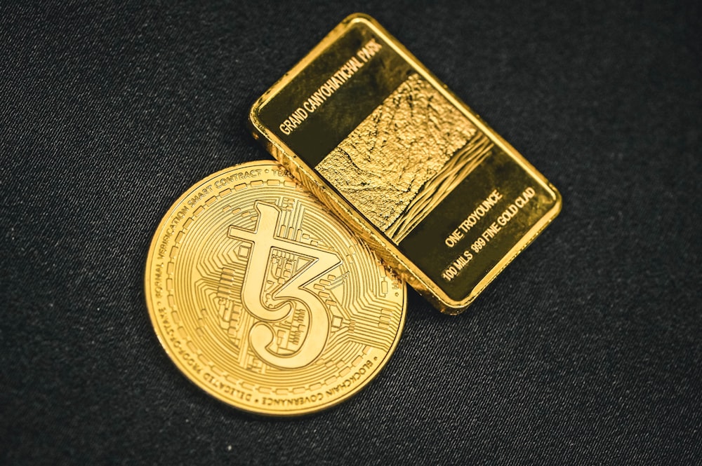 a gold bitcoin sitting on top of a black surface