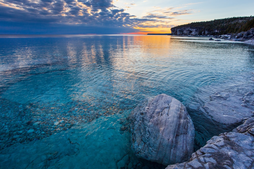 a large body of water with rocks in the foreground