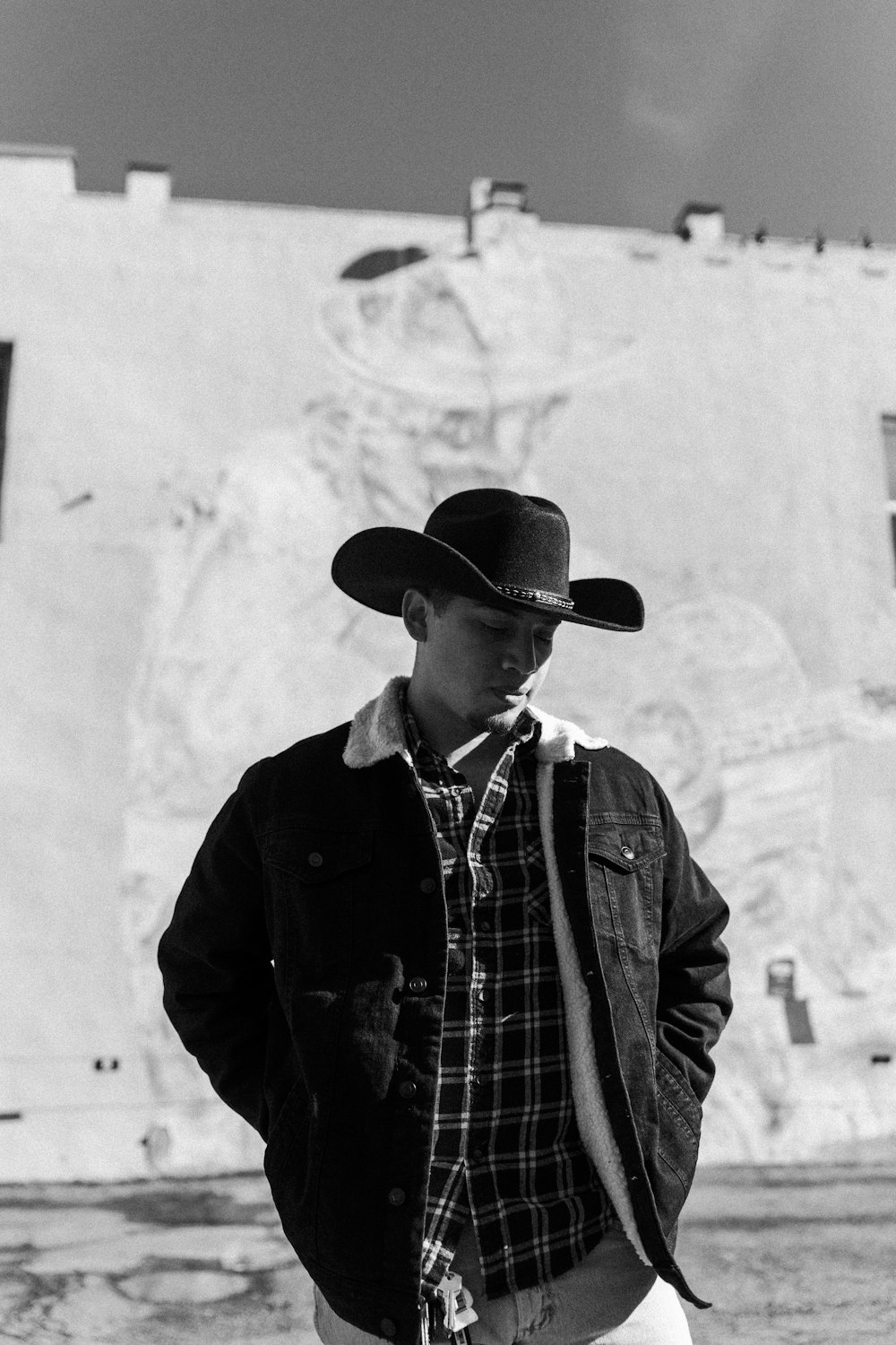 a man wearing a cowboy hat standing in front of a building