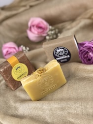 Artisan soap bars with natural textures and floral decorations arranged on linen fabric.