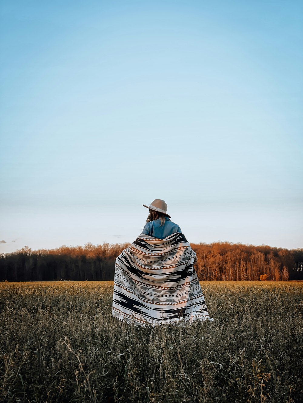 a person sitting in a field with a blanket