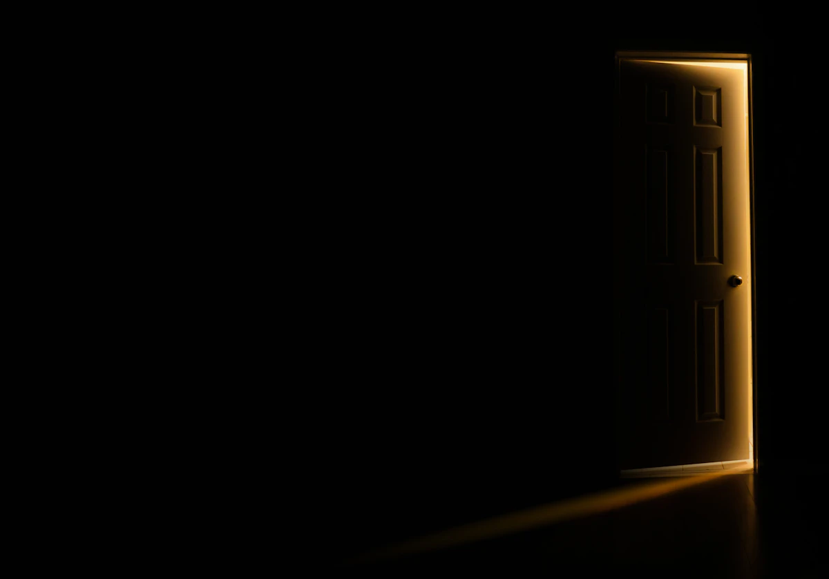 Pintu sedikit terbuka di ruangan gelap dengan seberkas cahaya masuk