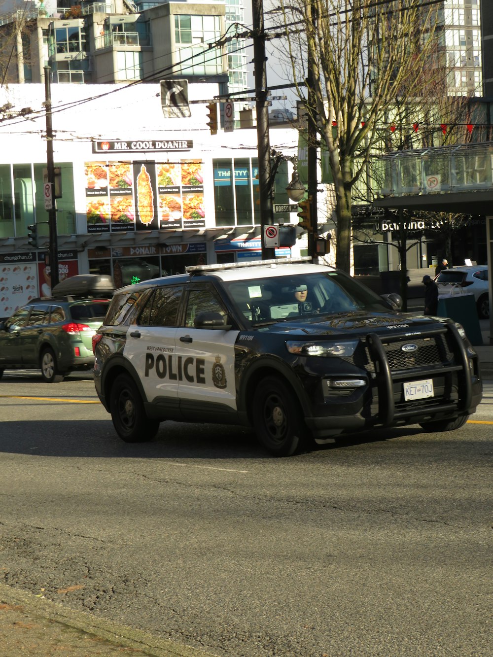 a police car driving down a street next to tall buildings