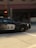 A police car from Vancouver is in motion on a city street. The car is a black and white vehicle with the word 'POLICE' and an emblem visible on the side. The background is blurred, indicating speed, and includes urban elements like an intersection and traffic lights.