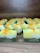 Multiple handmade soap bars are arranged in rows on a wooden surface. Each soap bar has a gradient appearance, transitioning from dark green at the bottom to yellow and white at the top. Small orange bits are sprinkled on the top of each soap bar. The brand name 'Himeriez' is embossed on each of the bars.