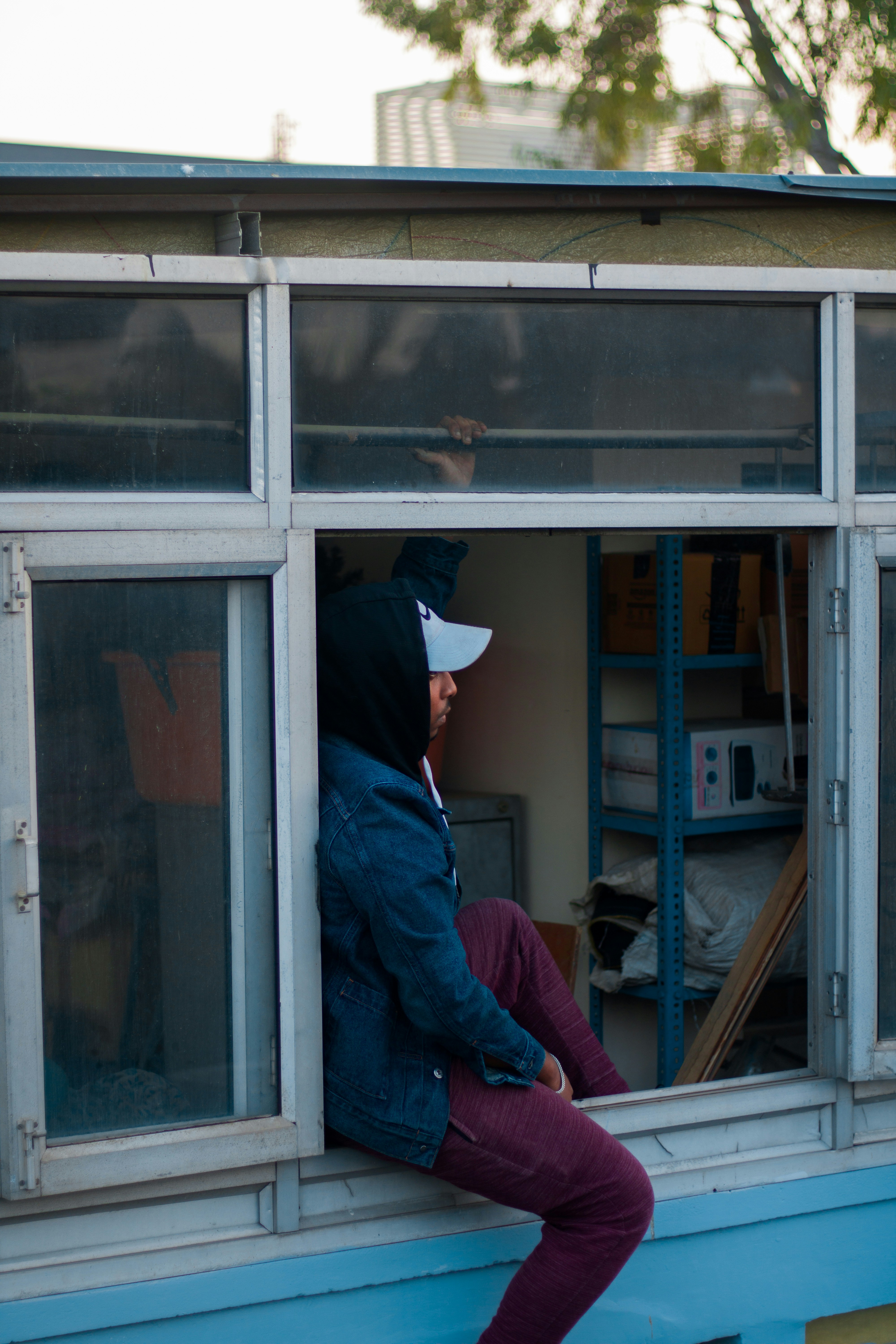 a person sitting on a window sill looking out