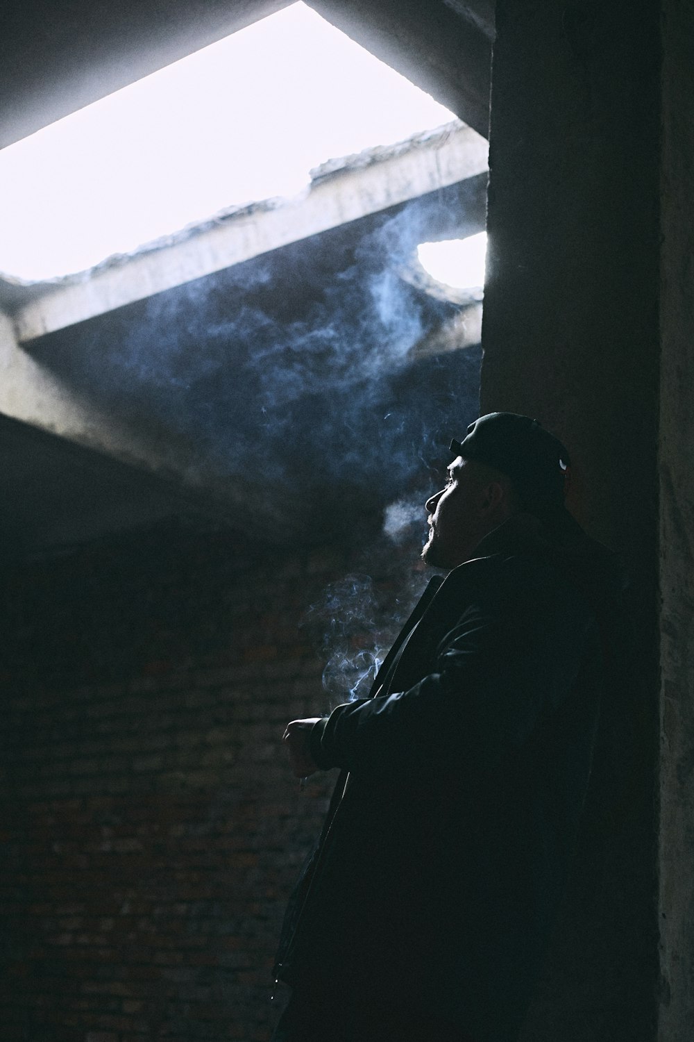 a man standing next to a brick wall