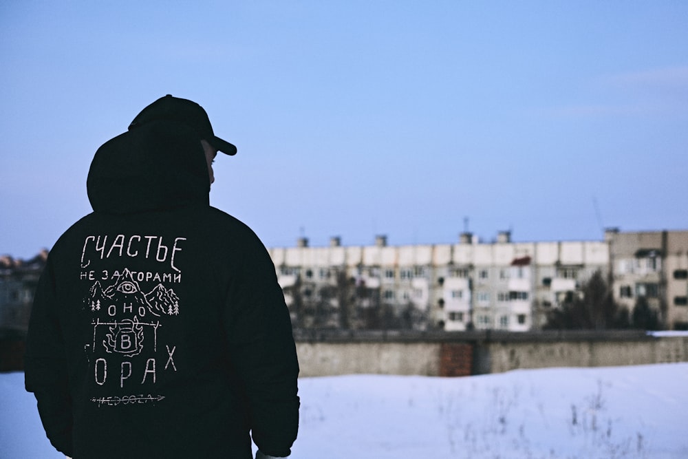 a man standing in the snow with a building in the background