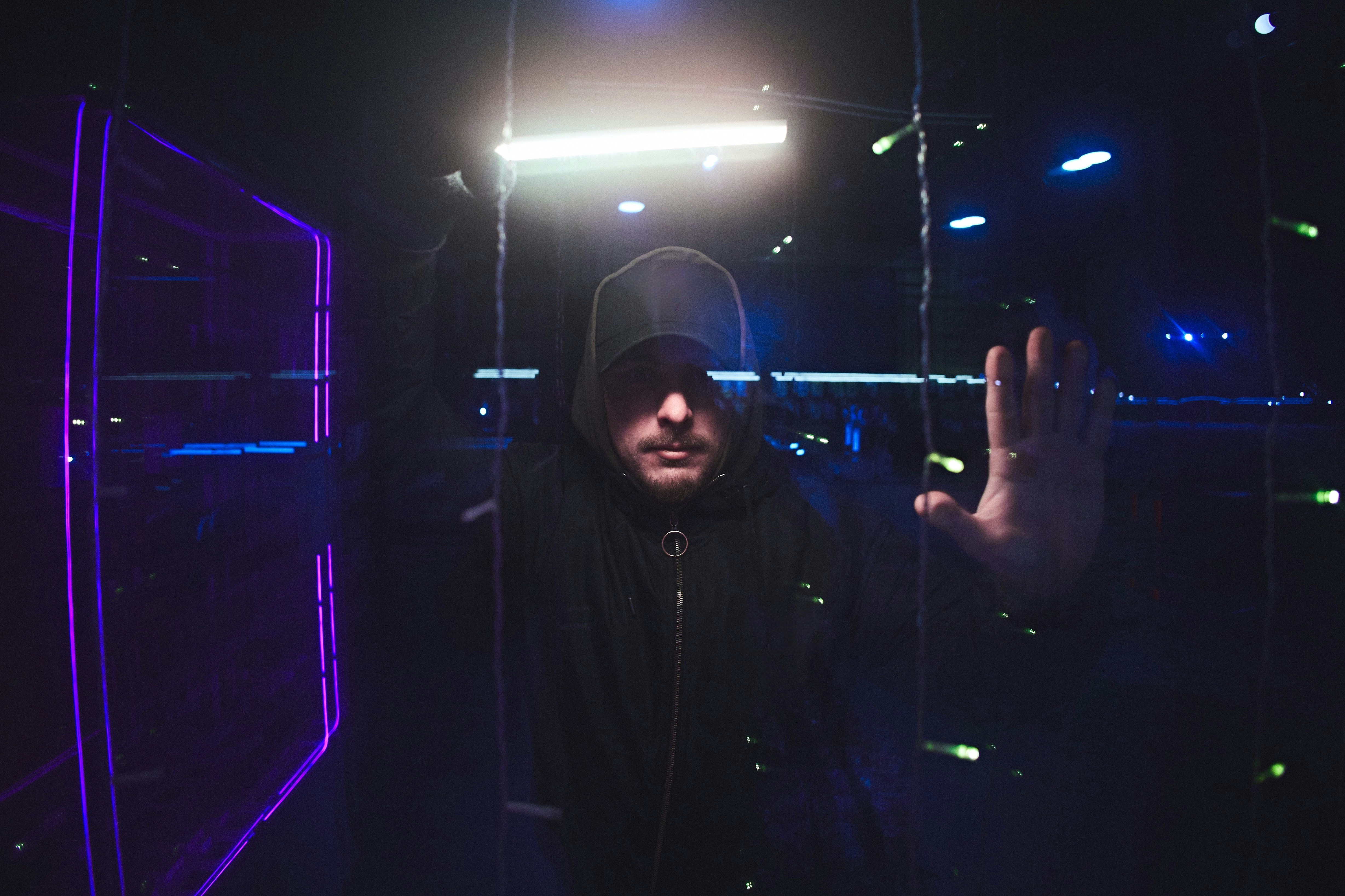 a man in a hooded jacket standing in a dark room