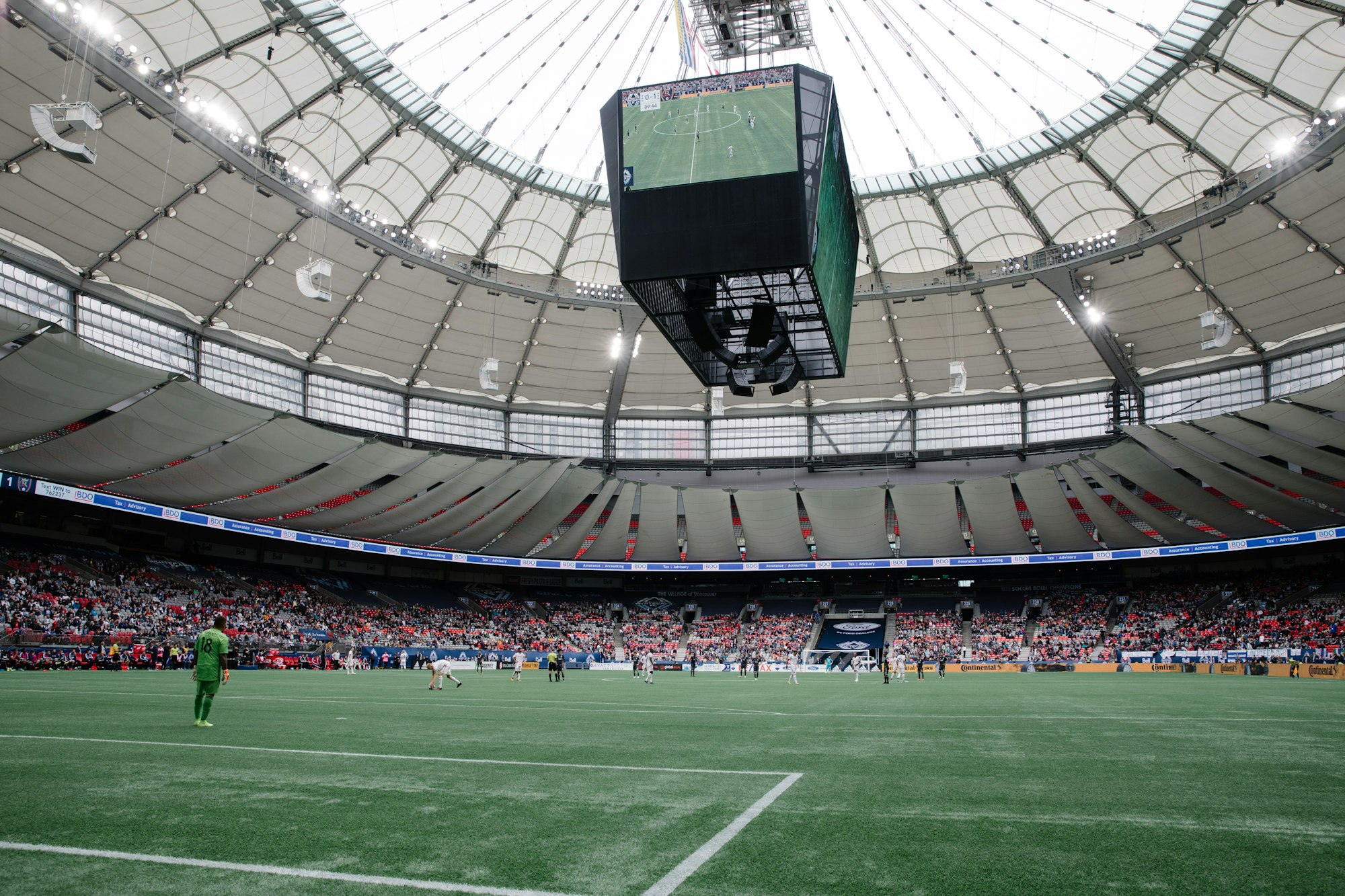 A soccer stadium with a large scoreboard and spectators.