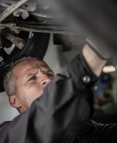 a man working on a car under a vehicle