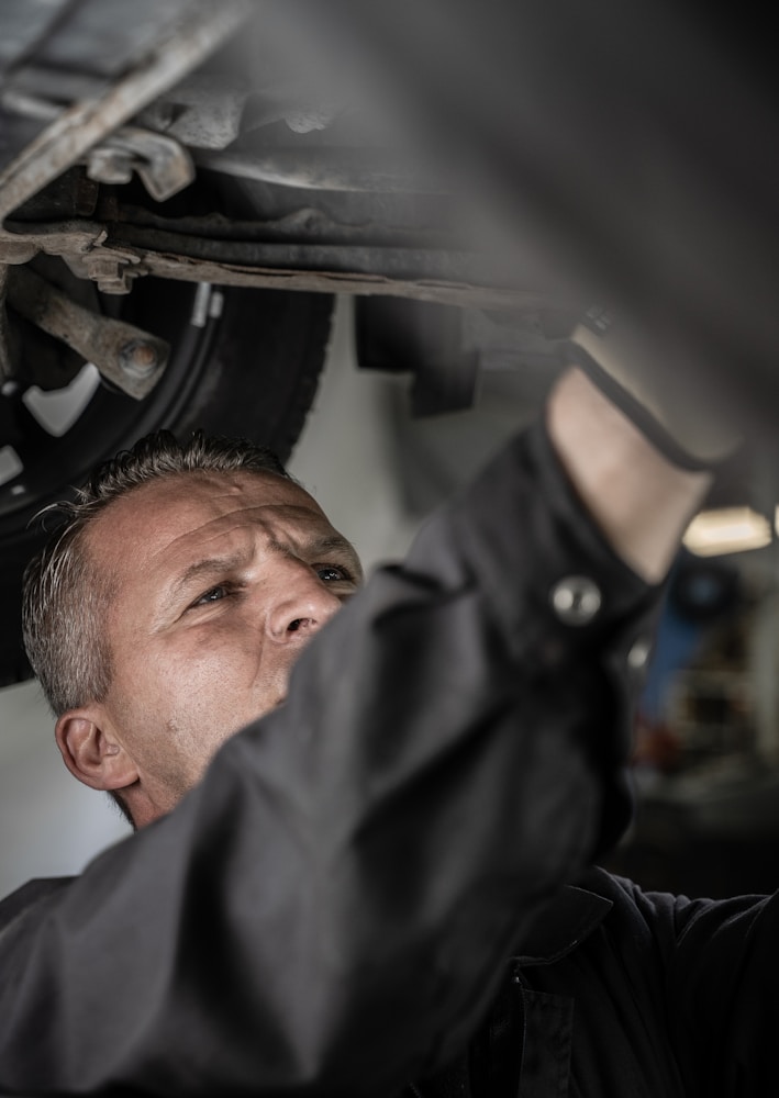 a man working on a car under a vehicle