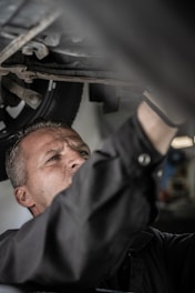 um mecânico tralhando na oficina embaixo de um ônibus