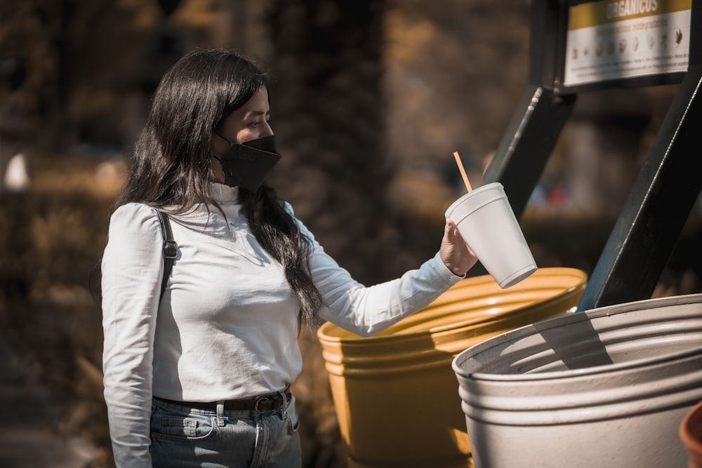 a woman in a white shirt is holding a cup