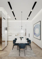 A contemporary kitchen remodel showcasing dark hardwood floors, minimalist pendant lights, and a bold blue accent wall.